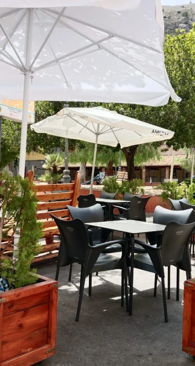 Terraza real de Hotel Anna, con mesas al aire libre bajo sombrillas blancas
